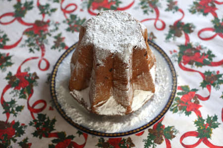 Traditional Italian panettone dessert for christmas. Homemade panettone closeup on a beautiful christmas tablecloth. Sweet bread served as dessert on tableの写真素材