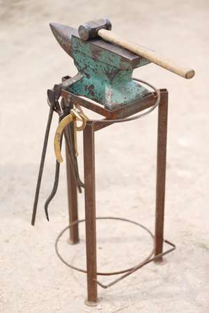 Farrier tools close up view at rural horse farm. Equestrian background. Equipment and hammer rest on...