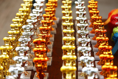 Award trophies waiting for competitors after amateur equestrian championship in row. Golden silver and bronze prizes for winners at an outdoor sport event. Colorful sport trophy backgroundの写真素材