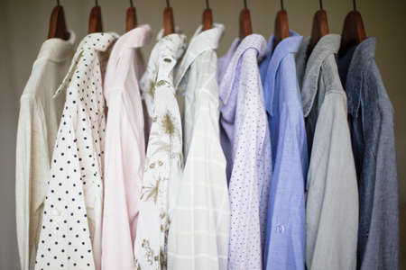 A row of assorted business shirts for women on hangers in a closetの写真素材