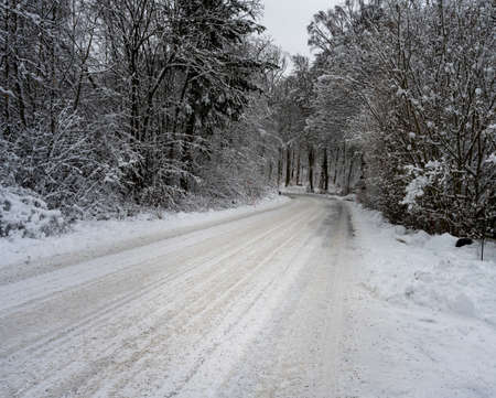 An icy and snowy winter road going through a forest. Picture from Scania, southern Swedenの写真素材