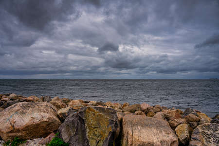 A beautiful, dramatic sky over the ocean. Stones in a wave breaker in the foreground. Picture from...