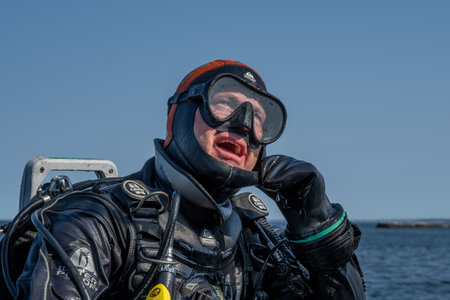 April 17, 2021 - Hamburgsund, Sweden: A scuba diver waiting for the dive boat to get into position so he can enter the water. Ocean and blue sky in the backgroundのeditorial素材