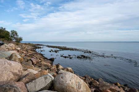 A rocky shoreline with blue water and a blu sky in the background. Picture from Skalderviken,...