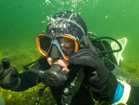 September 5, 2021 - Malmo, Sweden: A female scuba diver lit up by rays of sunlight penetrating the water. Scuba diving has been an increasingly popular sport during the coronavirus pandemicのeditorial素材