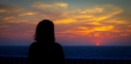 A woman meditating upon the setting sun