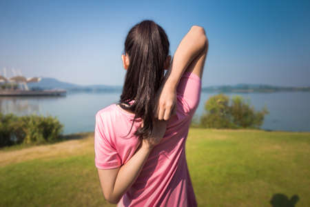 Young female workout before fitness training session at the park. Healthy young woman warming up...