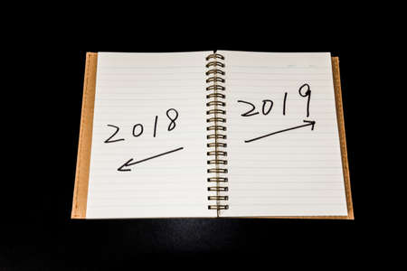 2019 resolution on blank notebook paper, smart phone with blank screen on white marble background,...