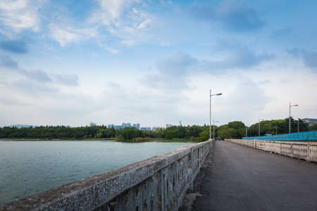 empty asphalt road near beautiful lake in blue sunny skyの写真素材