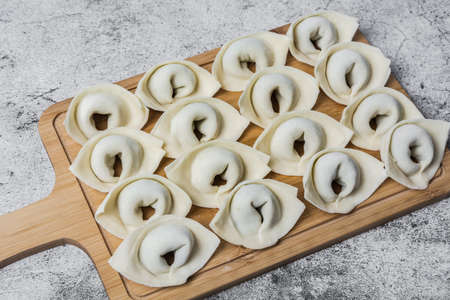 The process of making home-made dumplings. Raw homemade dumplings on a wooden board. Molding dumplings.の写真素材