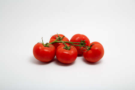Close up shot of a bunch of fresh red organic tomatoes isolated on white background with copy spaceの写真素材