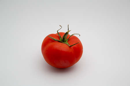 Close up shot of a fresh red organic tomato isolated on white background with copy spaceの写真素材