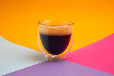 Freshly brewed creamy espresso in a glass coffee cup isolated on colorful background, close up with copy spaceの写真素材