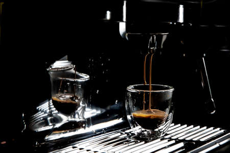 Dark coffee drops dripping in a transparent glass espresso cup on a manual espresso machine with copy space, close upの写真素材