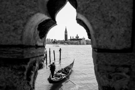 A gondolier rowing a Gondola in front of the Island of San Giorgio Maggiore, black and white, Venetian Lagoon, Venice, Italyのeditorial素材