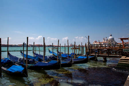 Traditional Grand Canal gondolas moored to pier, the Island of Giudecca and The Chiesa del Santissimo Redentore in the background, Venetian Lagoon, Venice, Italyのeditorial素材