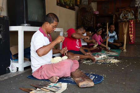 Balinese men and woman carving a wooden sculptures with chisels (carving knife), Bali, Indonesiaのeditorial素材
