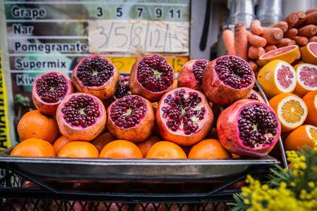 Fresh red pomegranates, oranges and carrots sold on a market place stallの写真素材