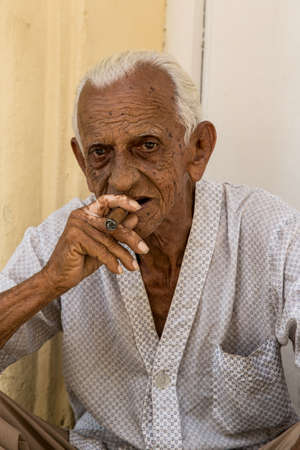 Havana / Cuba - 04.15.2015: Close up shot of an old Cuban man sitting on the street, smoking a cigar in the old town, Havana, Cubaのeditorial素材