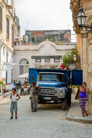 Havana / Cuba - 04.16.2015: Local Cuban men and woman standing on the street in front of an old blue truckのeditorial素材
