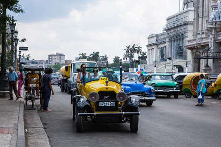 Havana / Cuba - 04.15.2015: Tourists riding a yellow classic car / taxi in front of the National Capitol buildingのeditorial素材