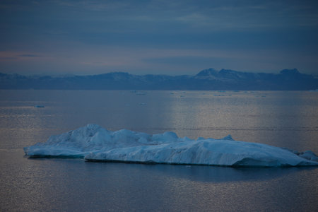 Antarctic landscape with icebergs in the ocean and mountains in the background