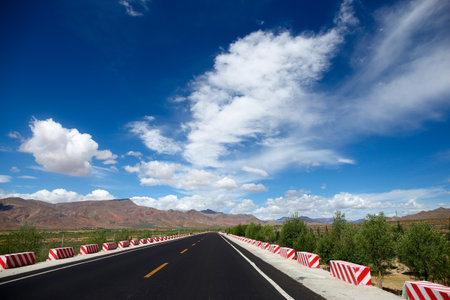 Road in the mountains with blue sky and white clouds on background.