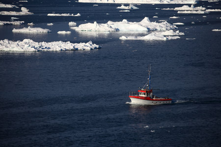 Fishing boat in the Antarctic waters with icebergs in the background