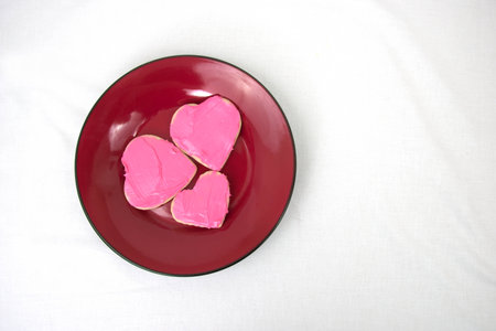 Plate of heart shaped cookies with pink frostingの写真素材
