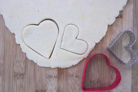 Heart-shaped cookie cutters with cookie doughの写真素材