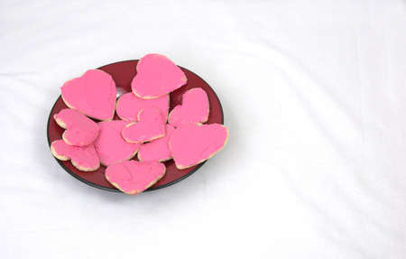 Plate of heart shaped cookies with pink frostingの写真素材