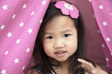 Female toddler portrait with pink fabricの写真素材