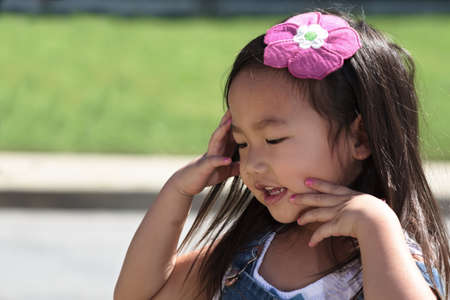 Female toddler with closed eyes and hands on faceの写真素材