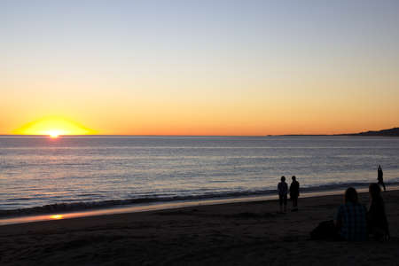 Sunset at beach with people watchingの写真素材