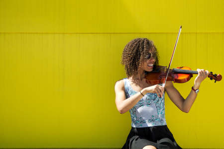 Smiling Young woman playing violin outsideの写真素材
