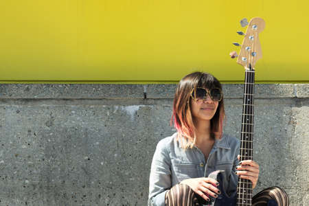 Young lady sitting on ground and posing with guitar