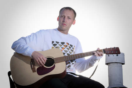 Male guitarist playing acoustic guitar outdoors