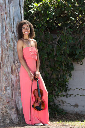 Smiling female violinist in long pink dress outsideの写真素材