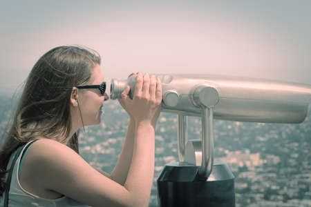 Young woman looking through coin binocularsの写真素材