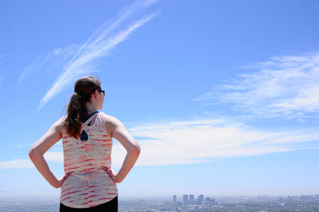 Woman with ponytail looking at city skylineの写真素材