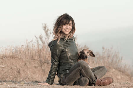 Seated woman with leather jacket and Dachshundの写真素材