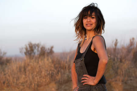 Young woman outdoors in overalls at sunsetの写真素材