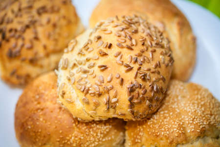 Fresh bread rolls with sunflower and sesame seeds on white plate table setの写真素材
