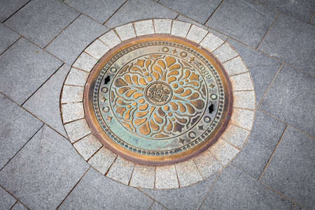Budapest rusted sewer cap surrounded by pavement granite stonesの写真素材