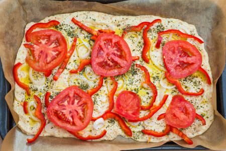 Delicious fresh traditional Italian focaccia bread with tomatoes, red peppers, onions, basil and...