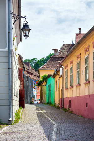 Sighisoara Romania  June 23 2013: Street lamp on old stone paved street with colored house from Sighisoara fortresss Transylvania Romaniaのeditorial素材