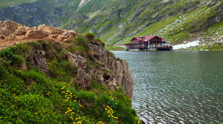 BALEA LAKE, ROMANIA - JUNE 24, 2012: Idyllic view with cottege on Balea Lake shore in Fagaras Mountains, Romania.のeditorial素材