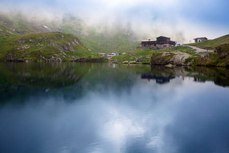 BALEA LAKE, ROMANIA - JUNE 24, 2012: Idyllic view with typical lodge on Balea Lake shore in Fagaras Mountains, Romania.のeditorial素材