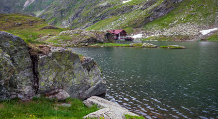 BALEA LAKE, ROMANIA - JUNE 24, 2012: Idyllic view with typical cottage on Balea Lake shore in Fagaras Mountains, Romania.のeditorial素材