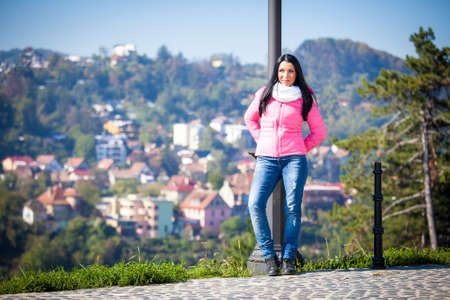 Young woman posing outdoor in autumn. Fashion portrait of pretty girl in cold weather wearing a pink jacket and jeans.の写真素材